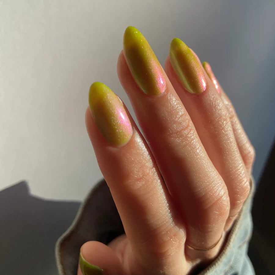 Hand with green and pink nail polish against a neutral background